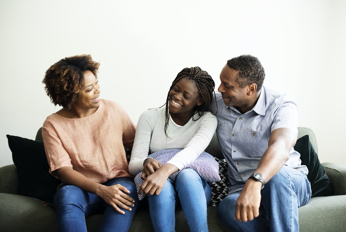 Black family on the couch. From left to right mother, daughter and father.